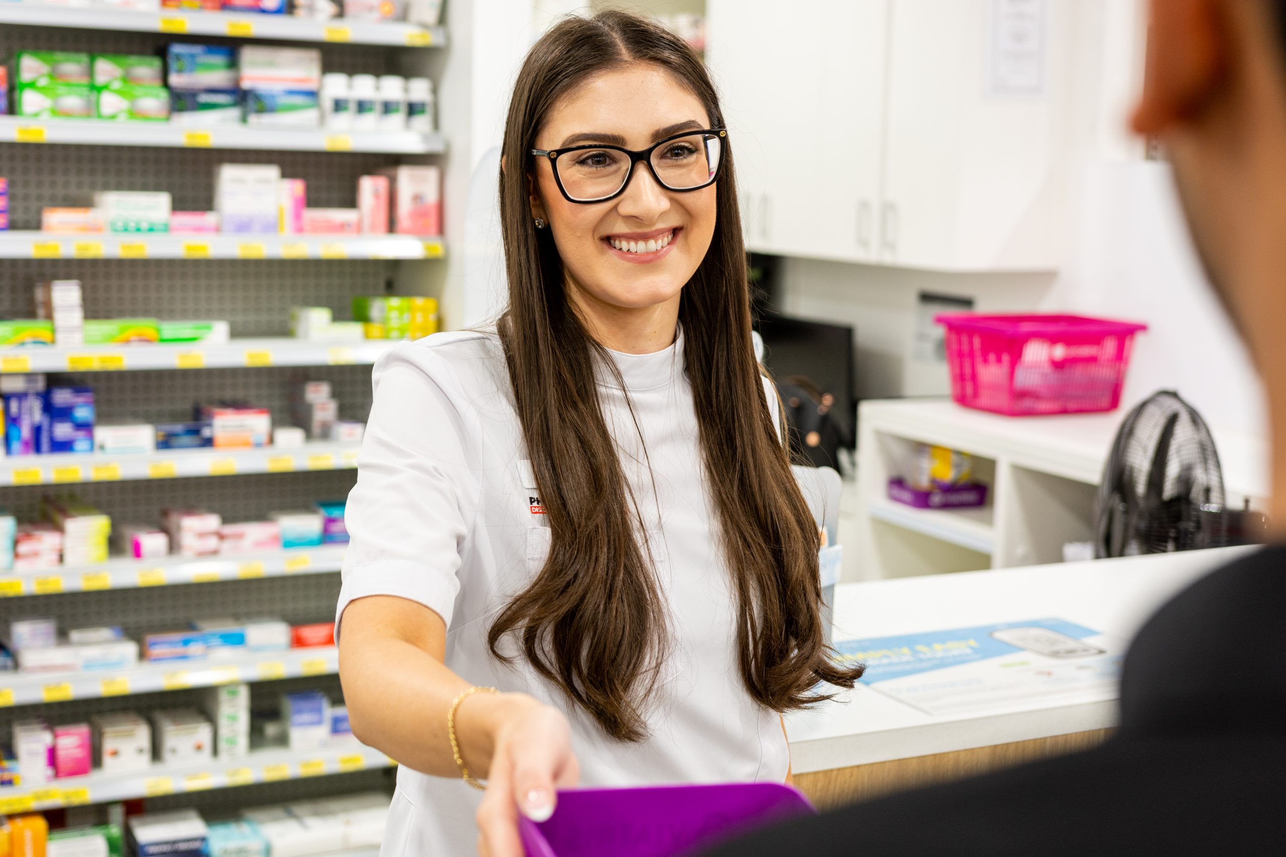Image of lady handing medication to customer at pharmacy